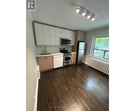 A kitchen with white cabinets and a wooden floor.