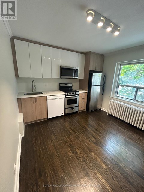 A kitchen with white cabinets and a wooden floor.