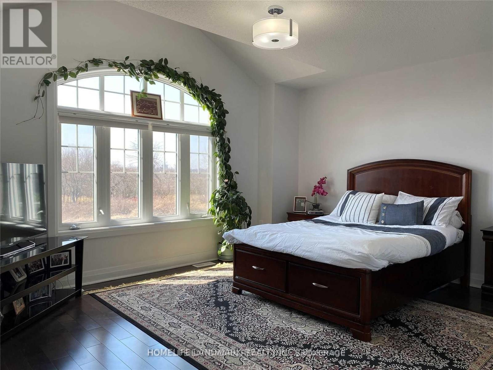 A bedroom with a bed, a window with a view, and a rug on the floor.