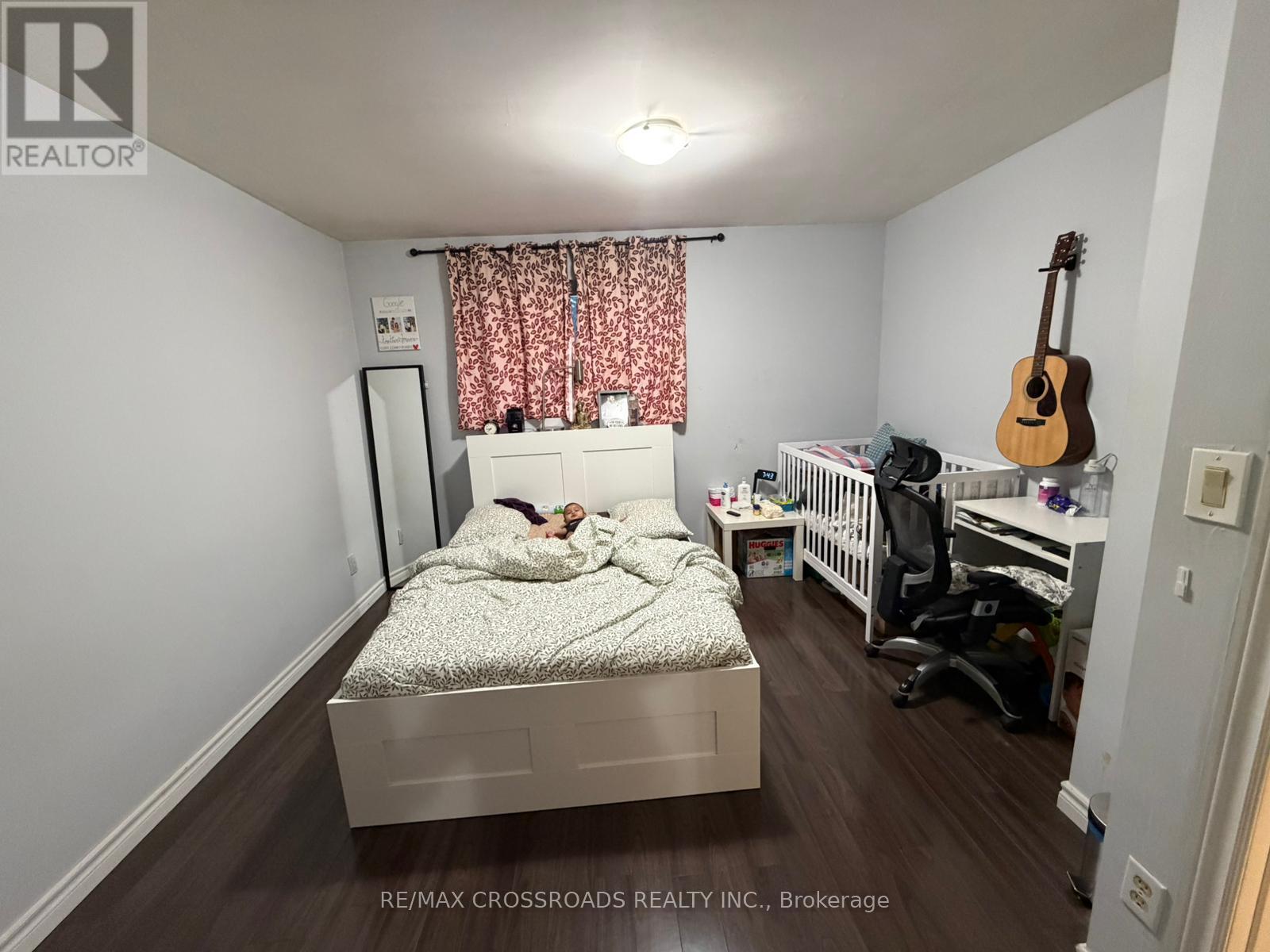 A bedroom with a bed, a crib, and a guitar.
