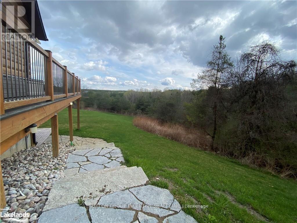 A wooden deck overlooks a grassy area with a cloudy sky above.