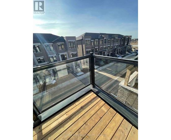 A balcony with a glass railing overlooking a residential area.