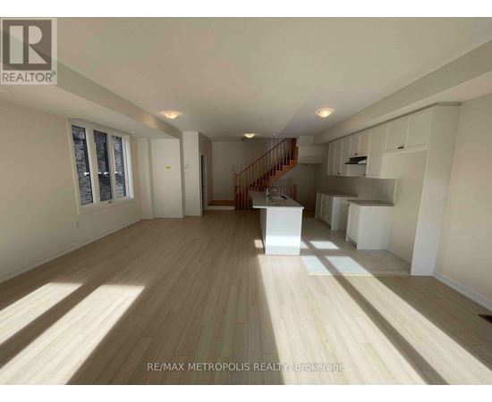 A spacious room with wooden flooring and a staircase leading to the upper level.
