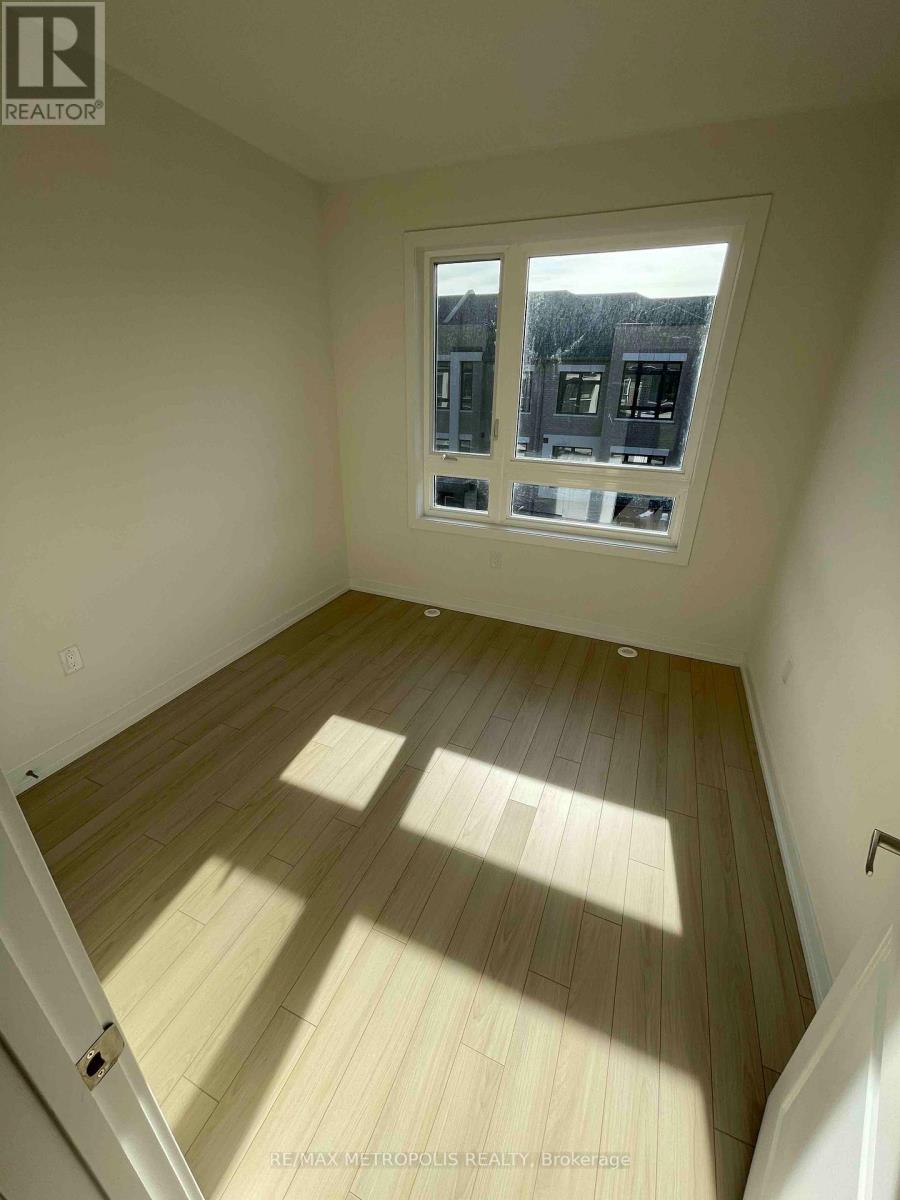 A room with wooden flooring and a window showing a view of houses.