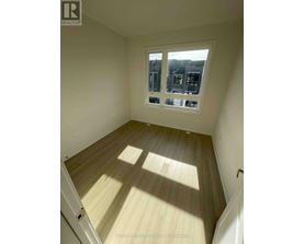 A room with wooden flooring and a window showing a view of houses.