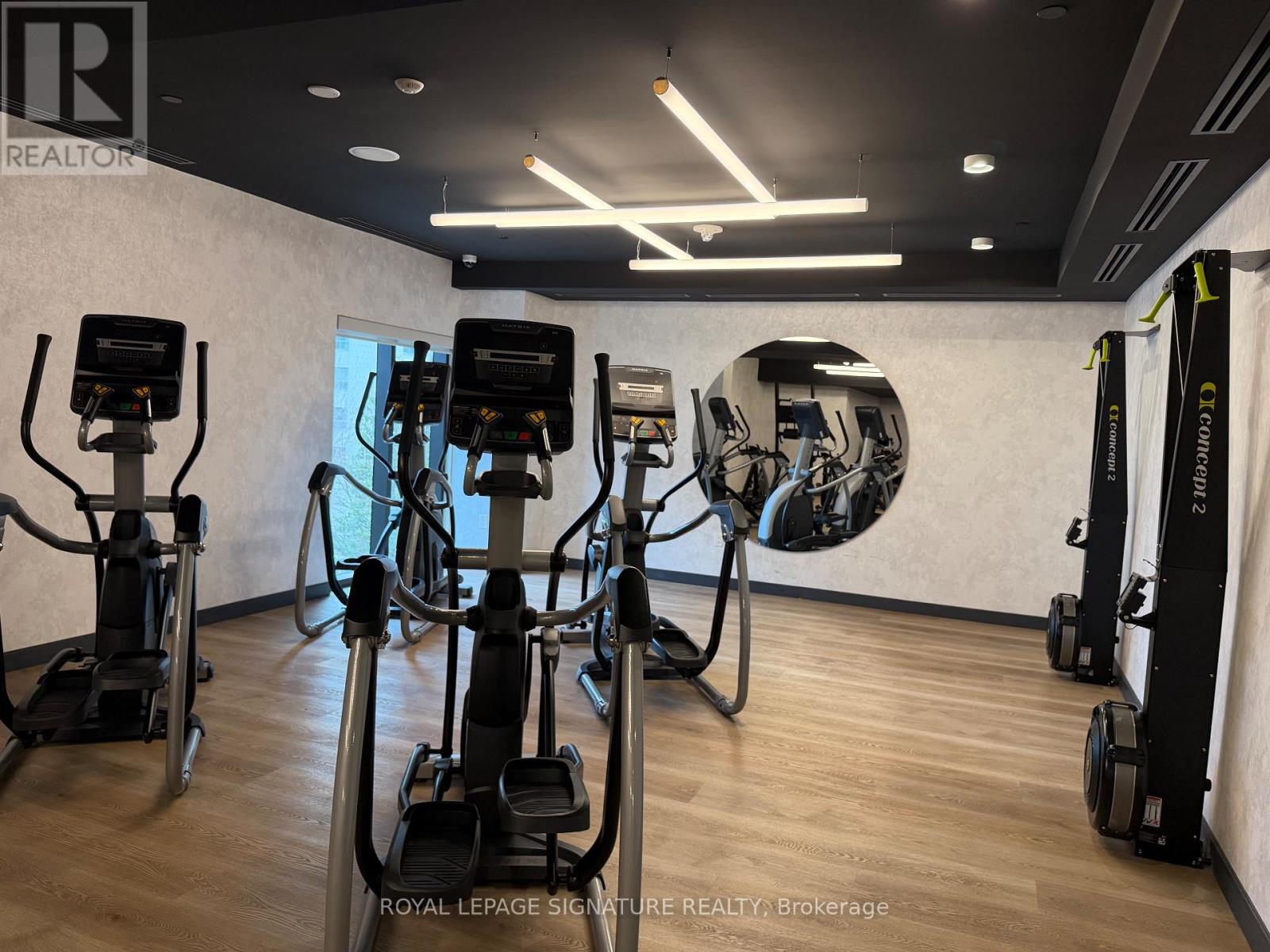 A gym with a row of treadmilers and elliptical machines.