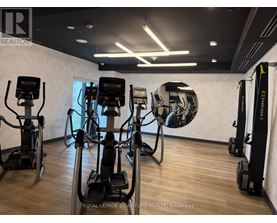 A gym with a row of treadmilers and elliptical machines.