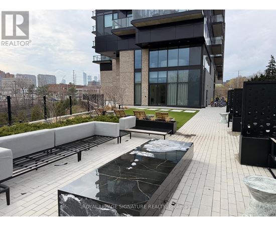 A modern building with a pool in the foreground and a fence surrounding the property.