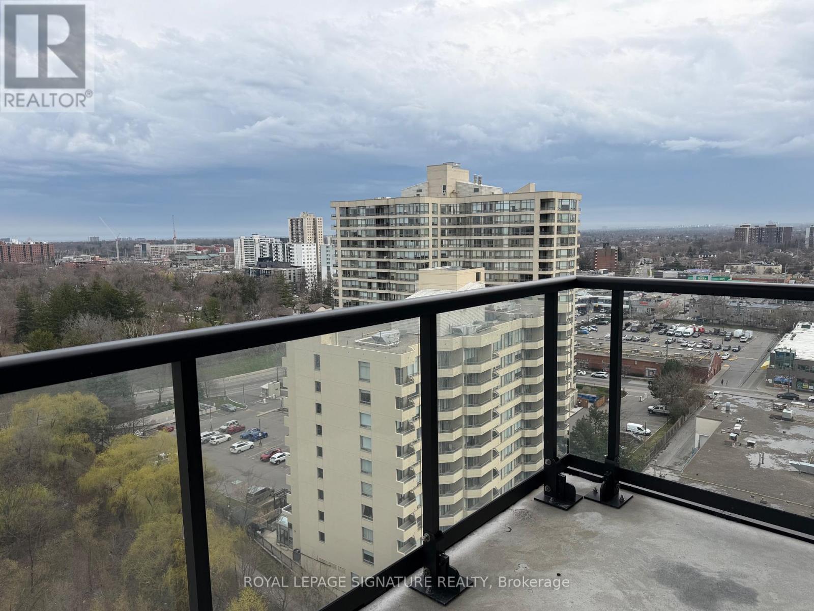 A view from a balcony of a multi-story building with a parking lot in the foreground.