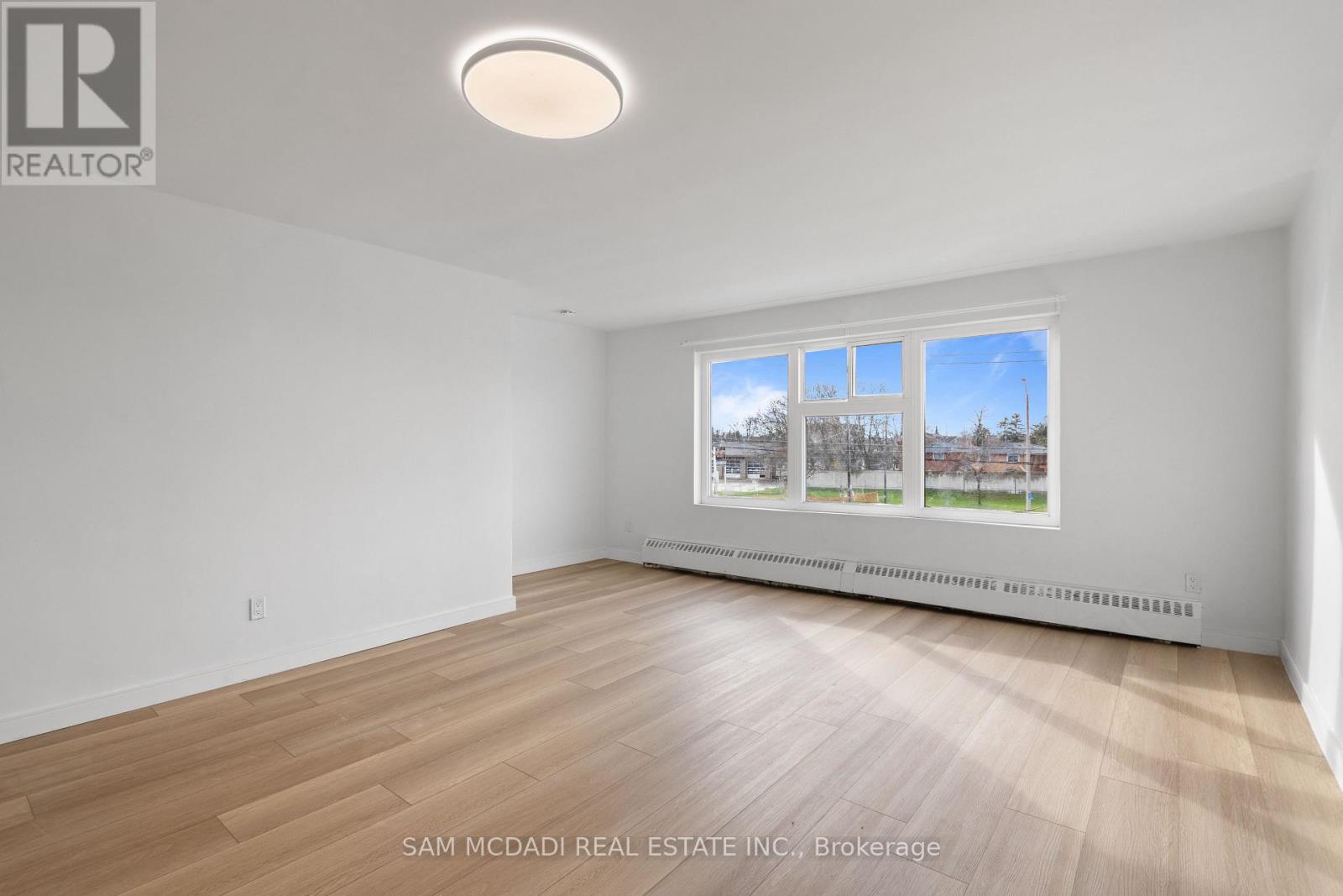 A room with a window showing a view of trees and a blue sky.