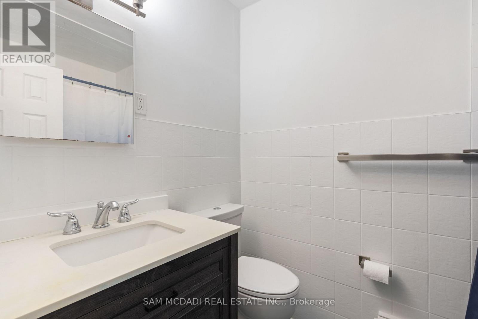 A bathroom with a sink, toilet and a mirror.