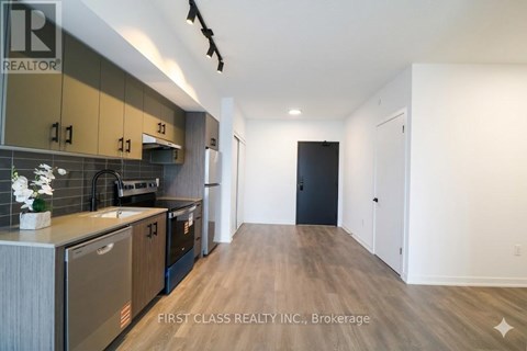 A kitchen with a refrigerator, cabinets, and a countertop.