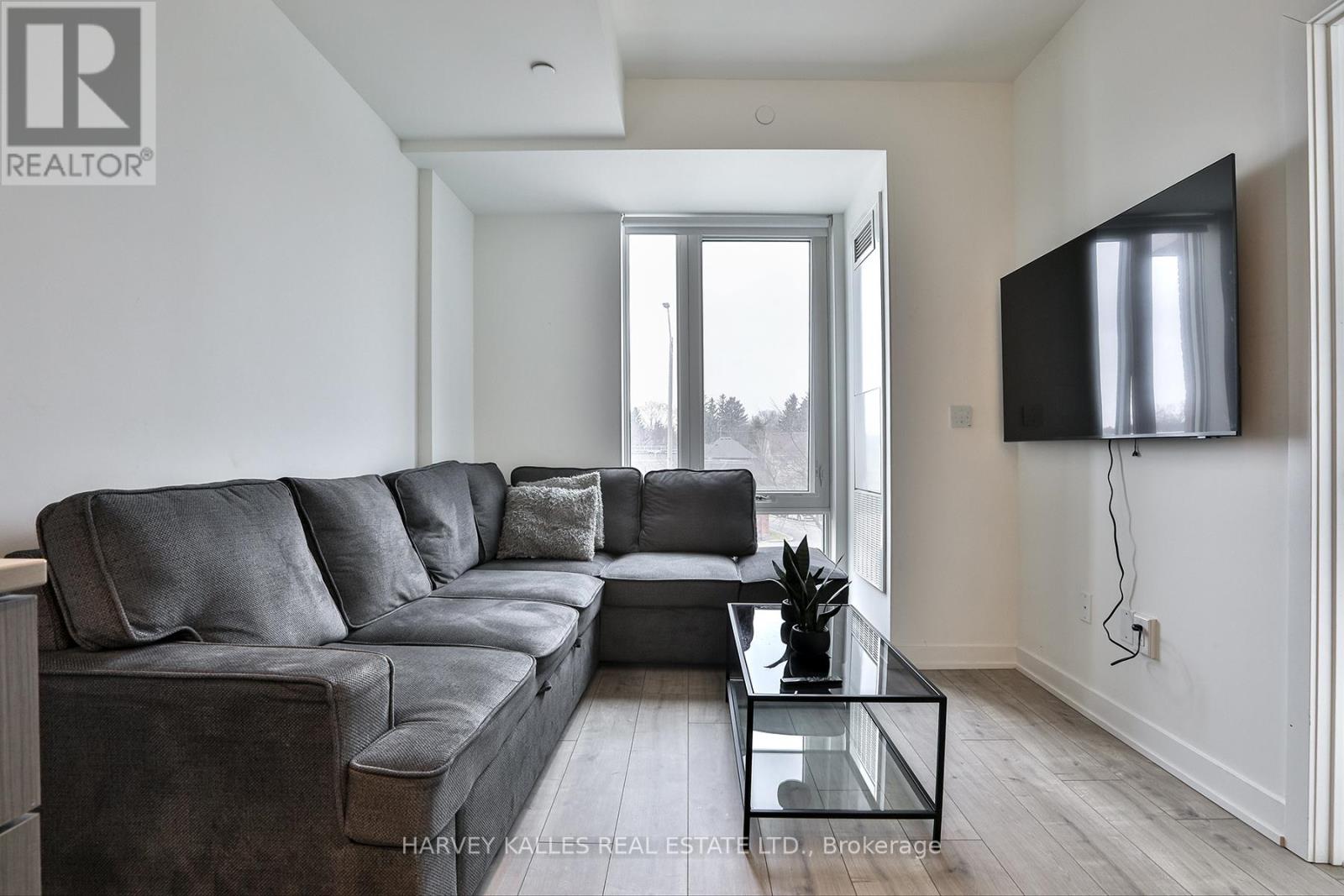 A modern living room with a grey sofa and a flat screen TV mounted on the wall.