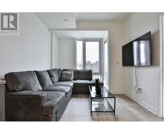 A modern living room with a grey sofa and a flat screen TV mounted on the wall.