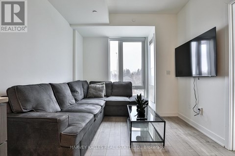 A modern living room with a grey sofa and a flat screen TV mounted on the wall.