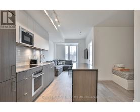 A modern kitchen with a microwave above the oven and a dining area with a couch and a TV.