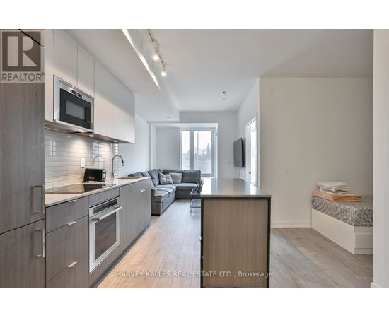 A modern kitchen with a microwave above the oven and a dining area with a couch and a TV.