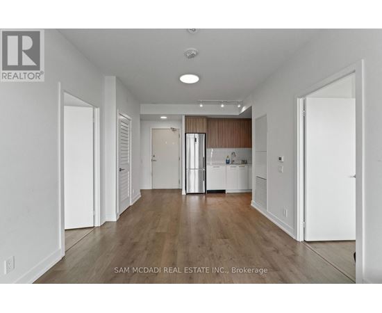 A large, empty room with wood flooring and white walls.