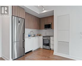 A kitchen with a refrigerator, oven, and microwave.