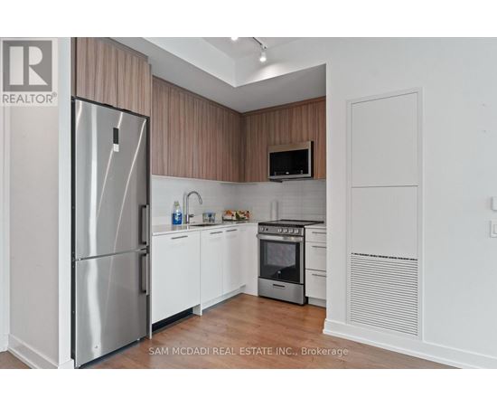 A kitchen with a refrigerator, oven, and microwave.