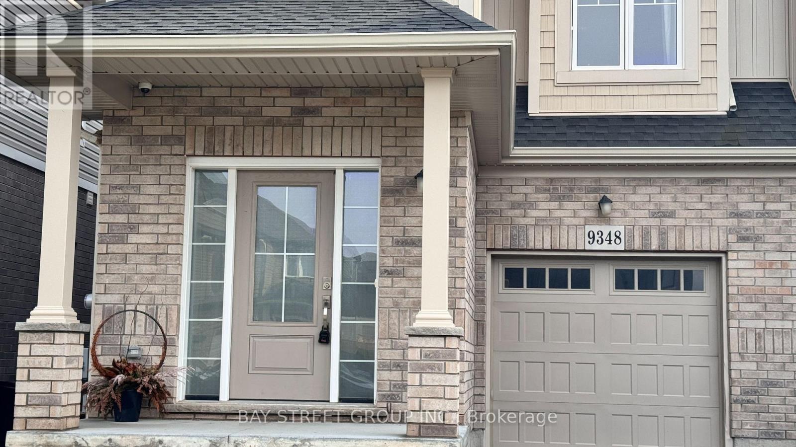 A house with a grey garage door and a brown door with a glass window.