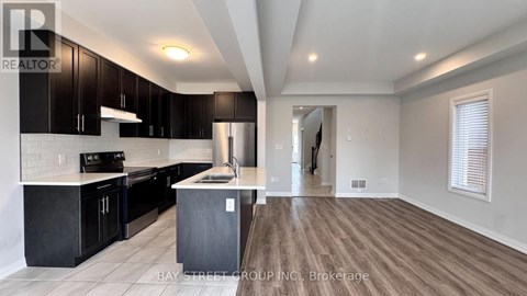 A modern kitchen with black cabinets and a wooden floor.