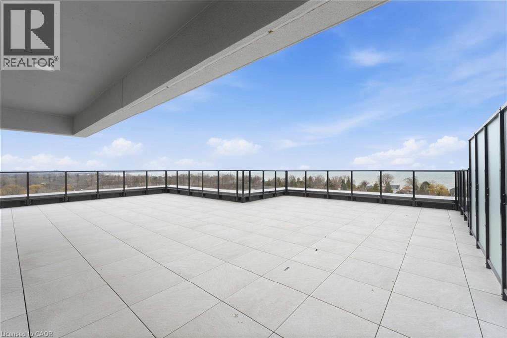 A rooftop patio with a glass railing and a clear sky.