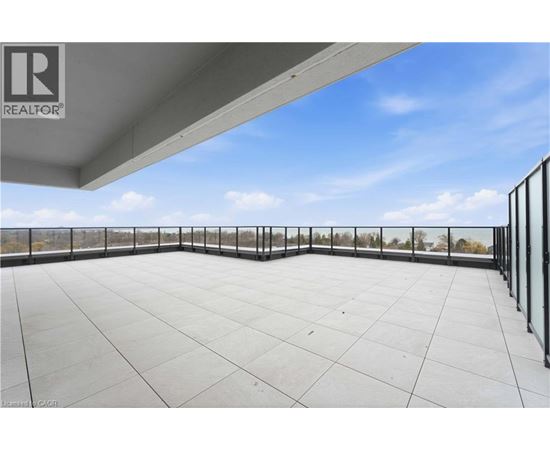 A rooftop patio with a glass railing and a clear sky.