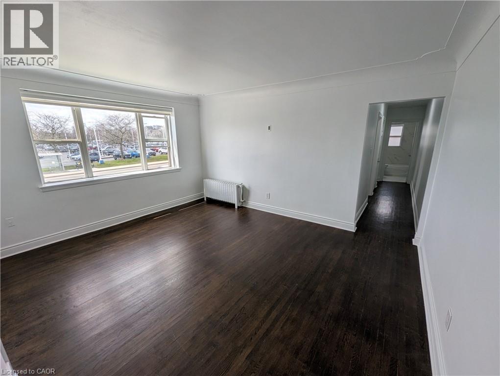 A room with wooden floors and white walls, with a window showing an outdoor view.
