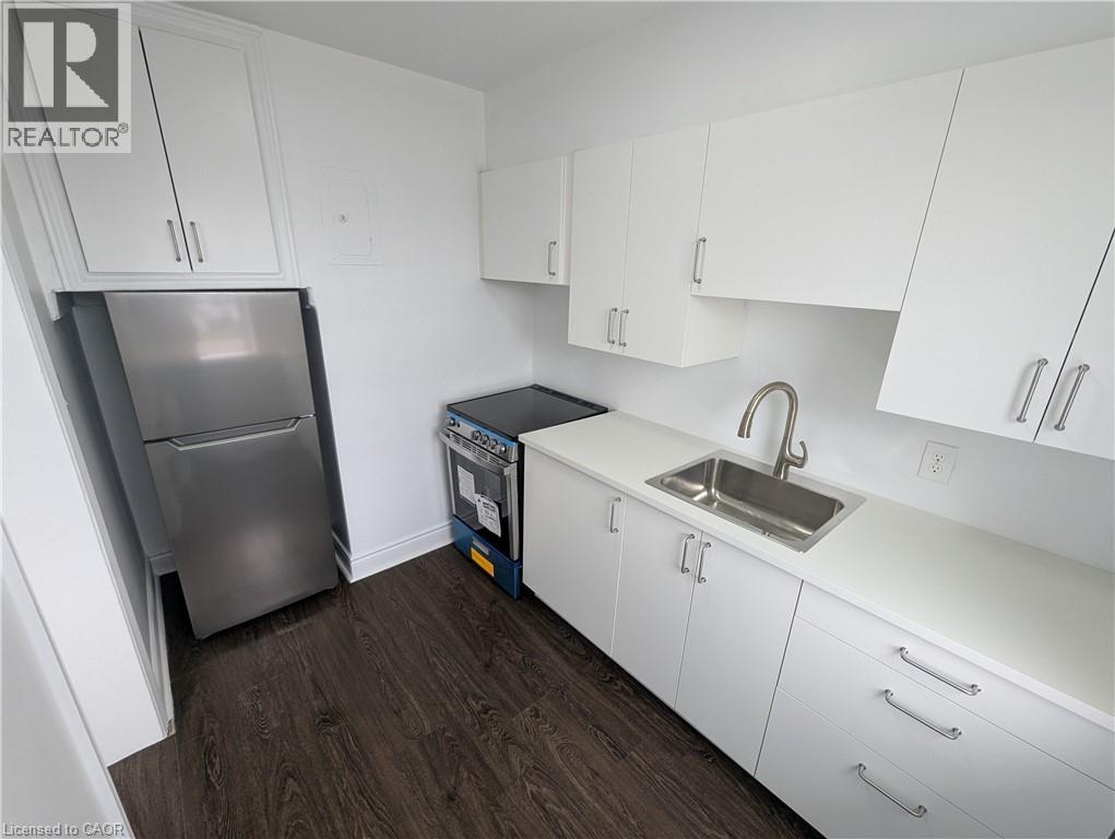 A kitchen with white cabinets and a stainless steel refrigerator.