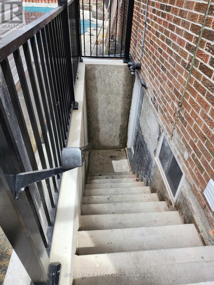 A stairway with a black railing and a brick wall.