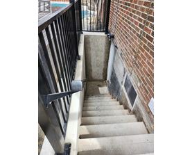 A stairway with a black railing and a brick wall.