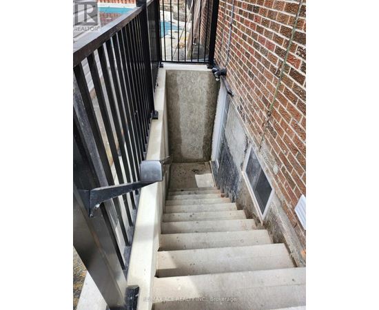 A stairway with a black railing and a brick wall.