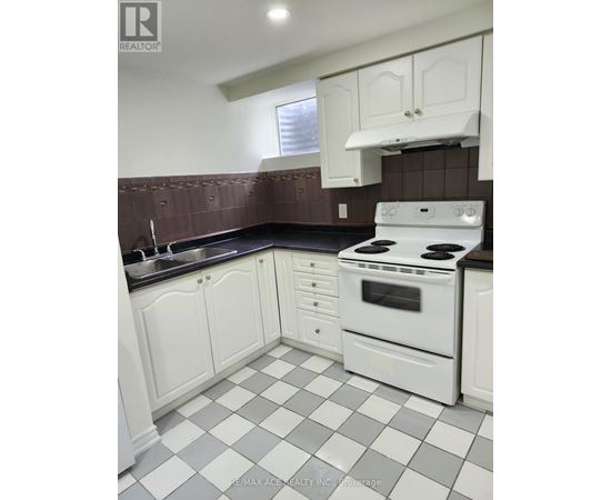 A white stove and oven in a kitchen with white cabinets and a checkered floor.
