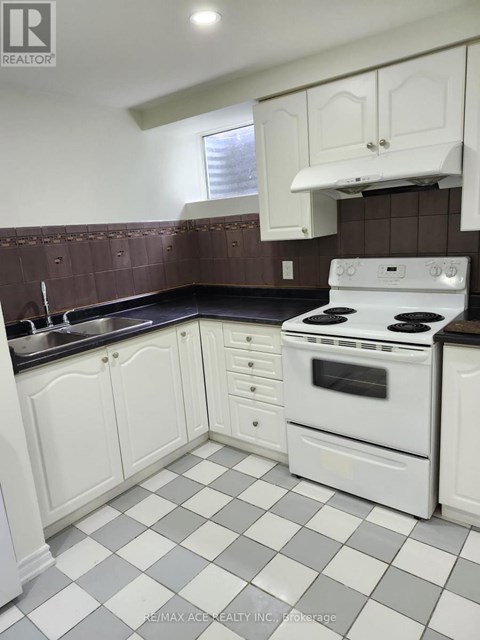 A white stove and oven in a kitchen with white cabinets and a checkered floor.