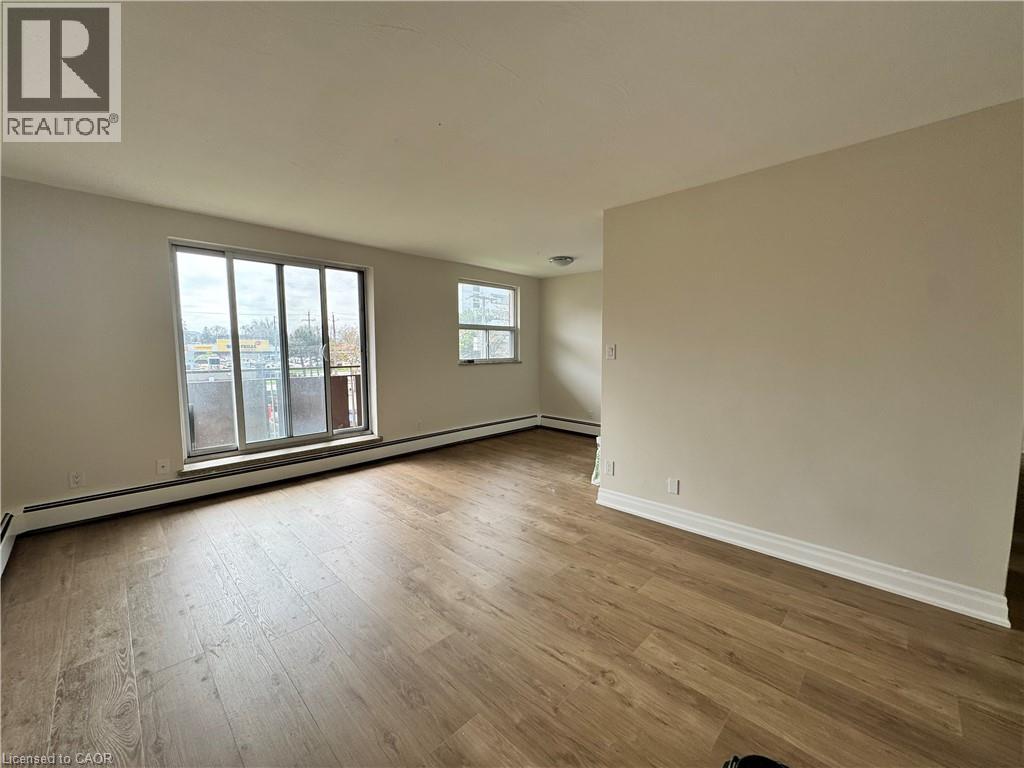 A room with wooden flooring and two windows.