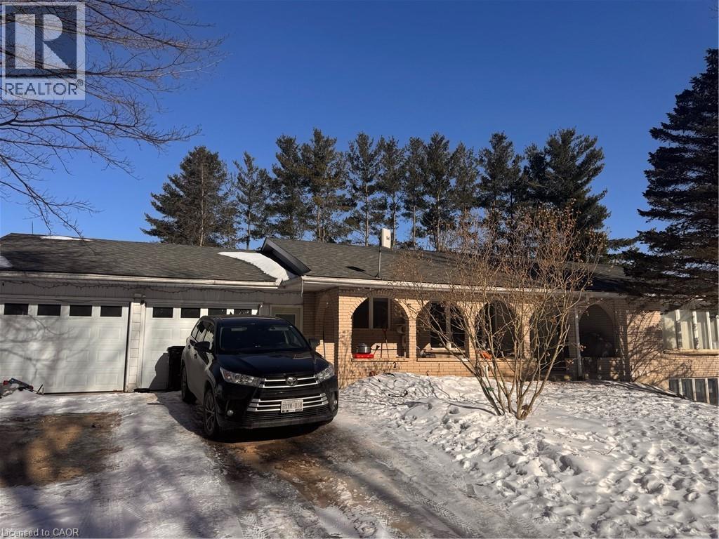 A black car is parked in front of a house with snow on the ground.