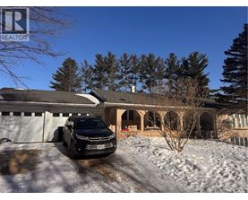 A black car is parked in front of a house with snow on the ground.