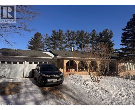A black car is parked in front of a house with snow on the ground.