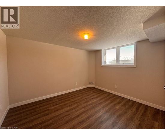 A room with wooden flooring and a window with blinds.