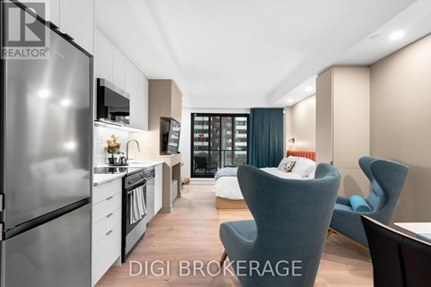 A modern kitchen with a refrigerator, a dining table with chairs, and a living area with a couch.