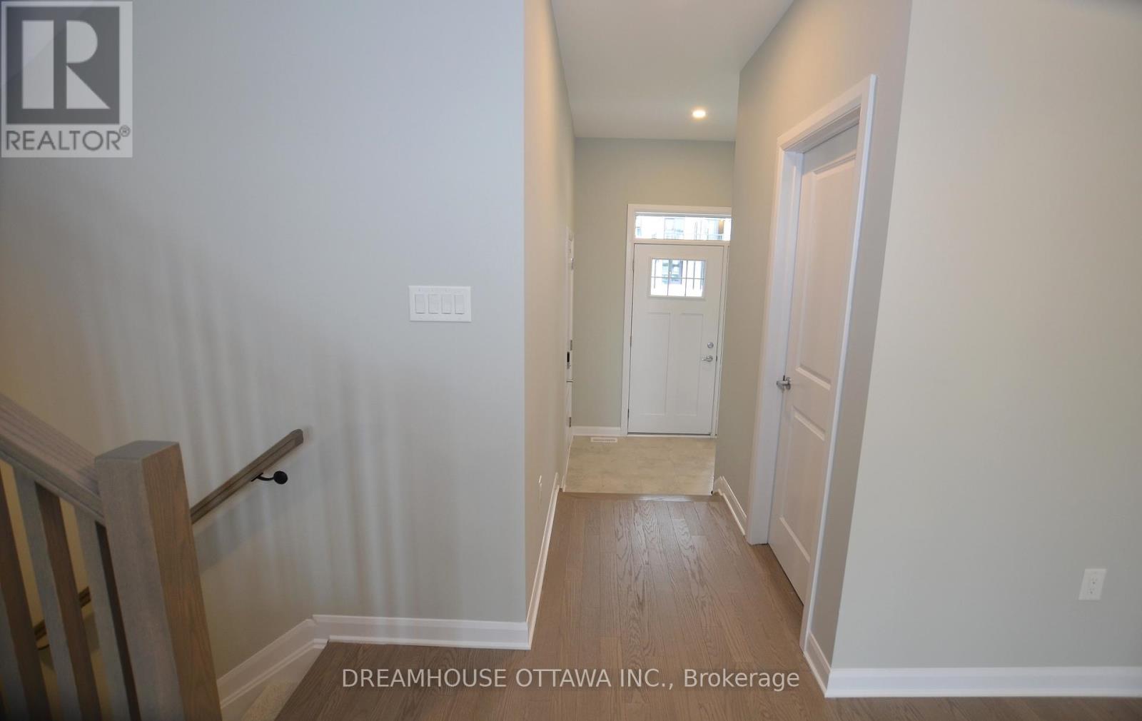 A hallway with a door on the right and a staircase on the left.