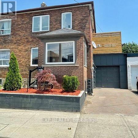 A brick house with a garage door and a small garden in front.