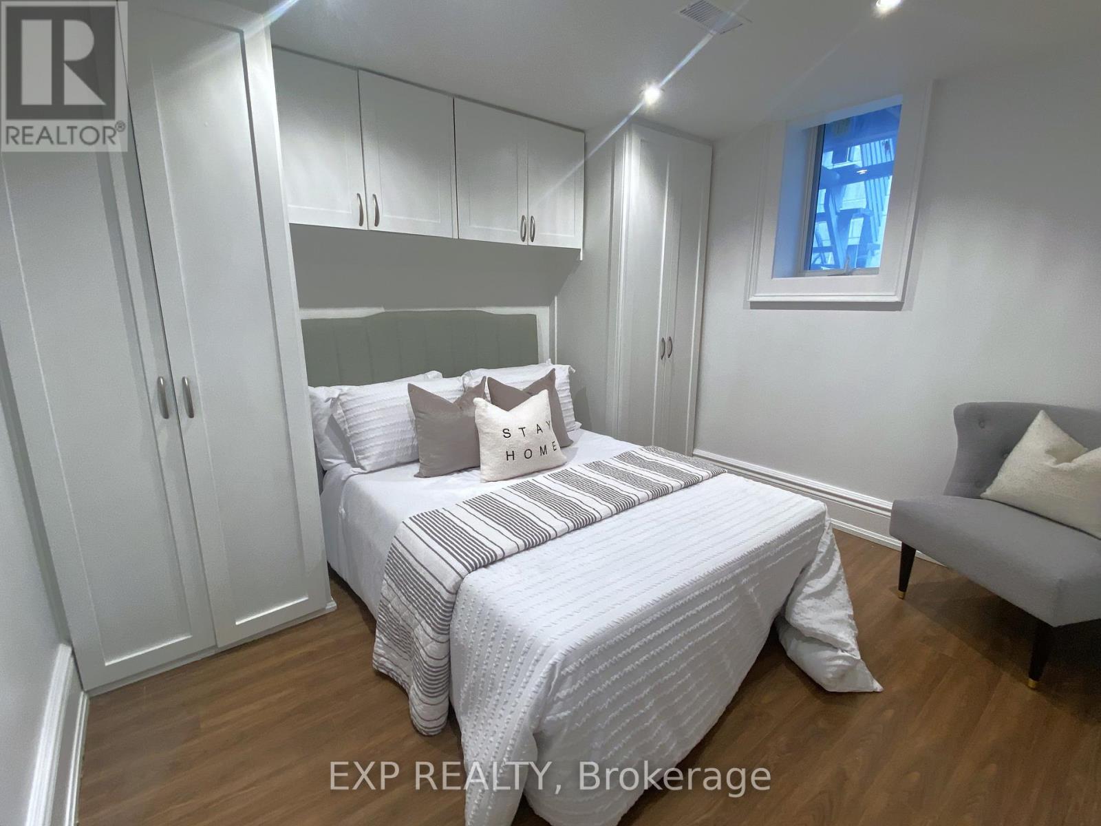 A bedroom with a bed, a chair, and a window.