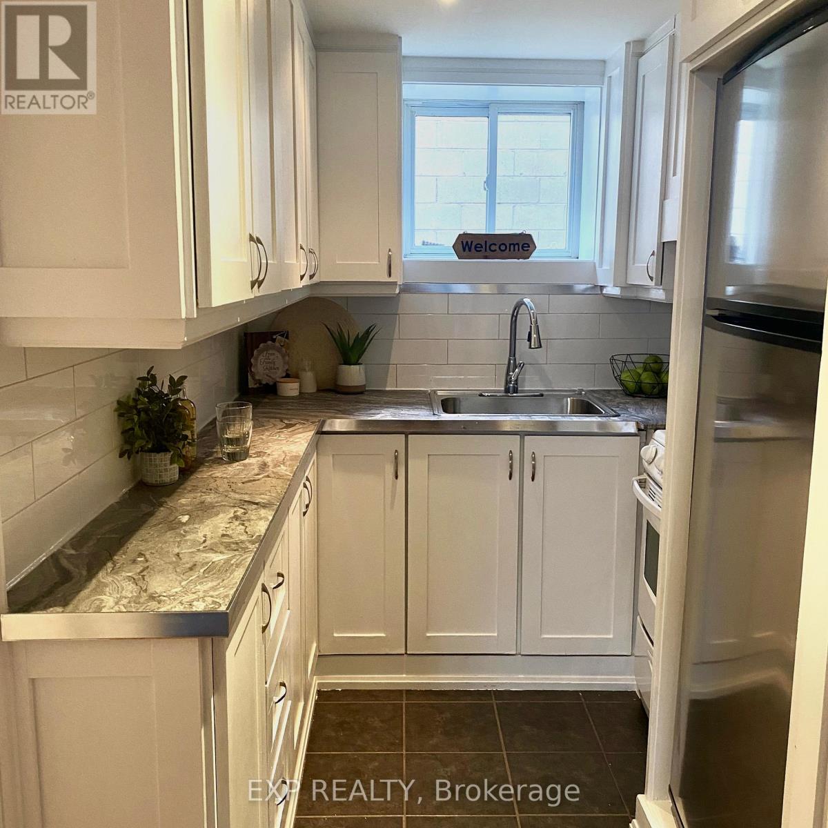 A kitchen with white cabinets and a marble countertop.