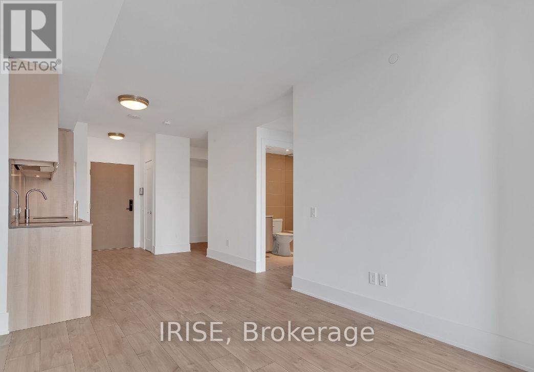 A spacious, empty room with a sink and a brokerage sign.