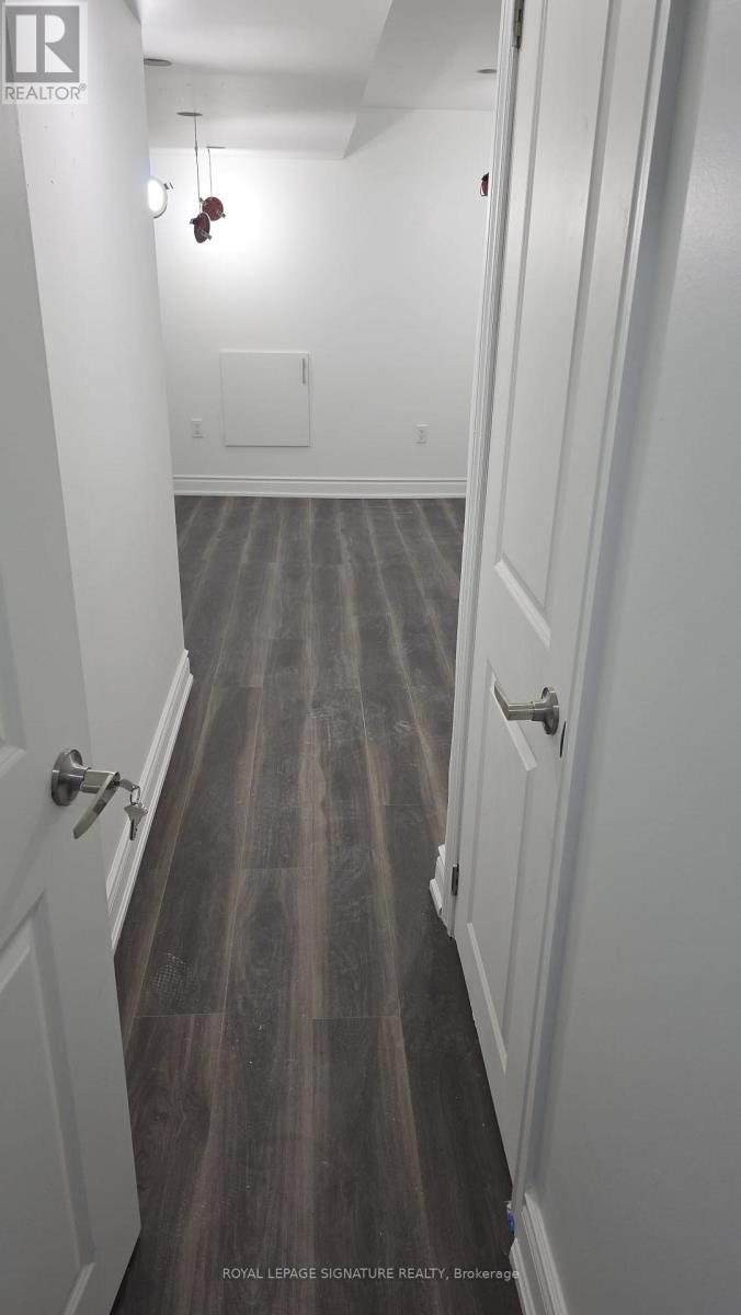 A long hallway with white walls and wood floors.
