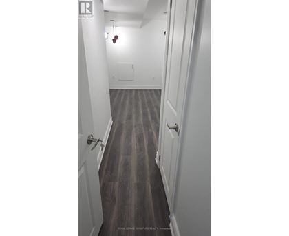 A long hallway with white walls and wood floors.