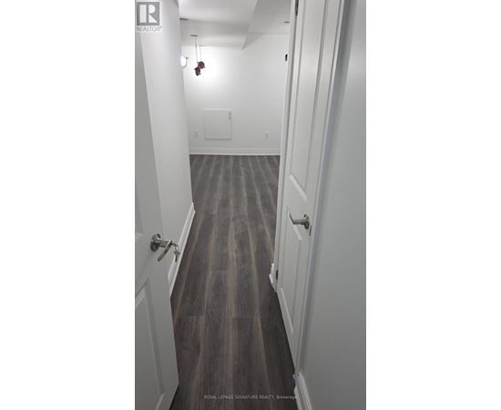 A long hallway with white walls and wood floors.