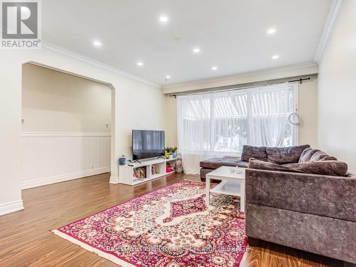 A living room with a grey couch and a red rug.